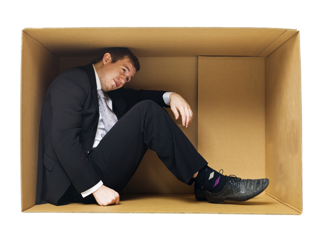 Man hunched over inside of a box