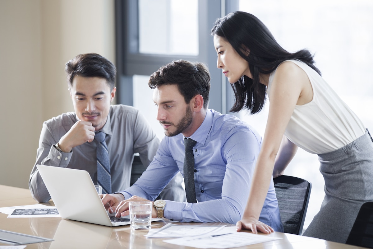 Businessmen and woman working on laptop during meeting